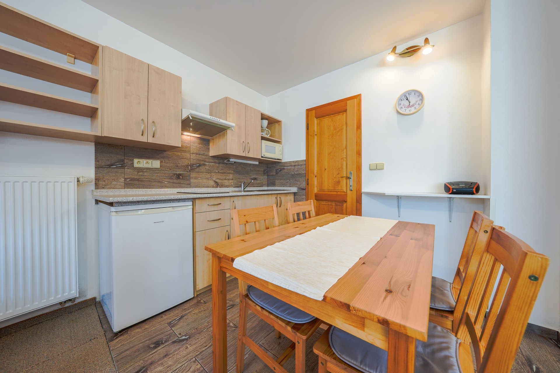 Apartmán 1 – kuchyňský kout s jídelním stolem a lednicí